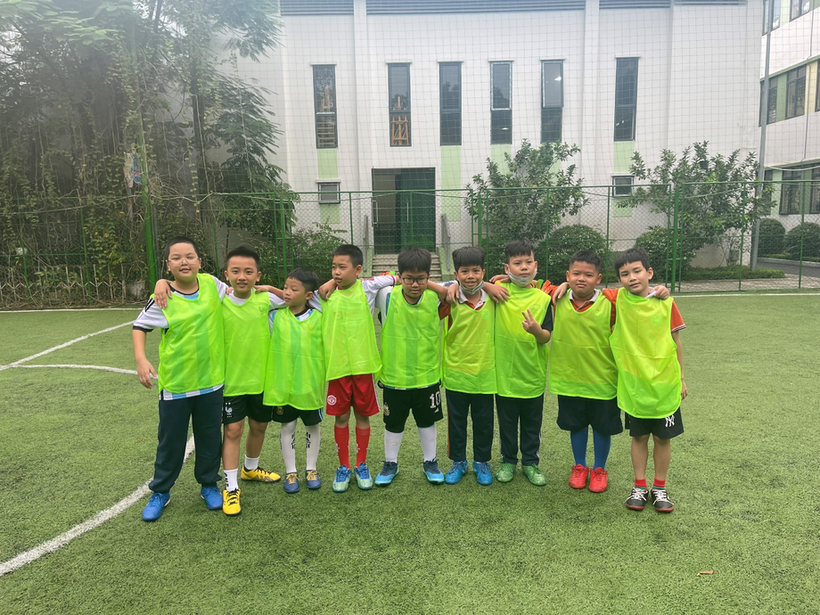 A group of boys wearing green vests standing on a football fieldDescription automatically generated