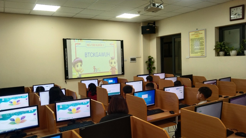 A classroom with computers and a large screen

Description automatically generated