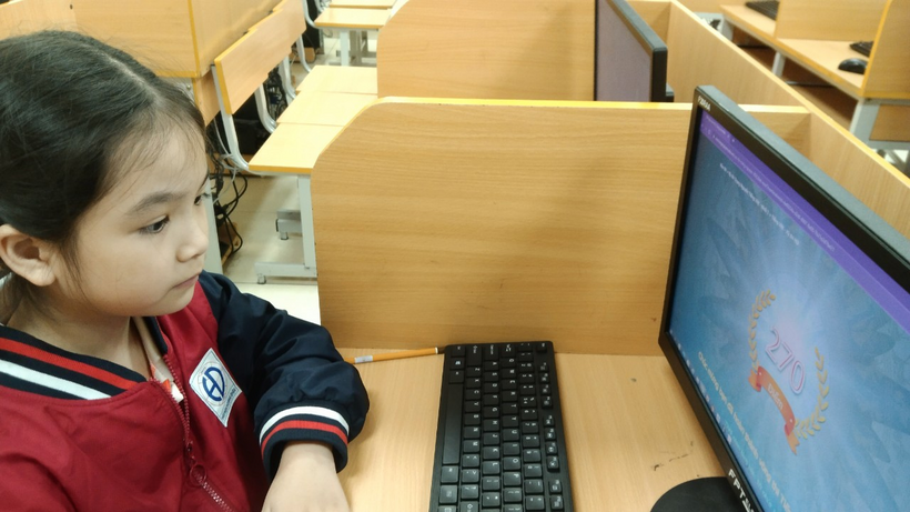 A child sitting at a desk with a computer

Description automatically generated