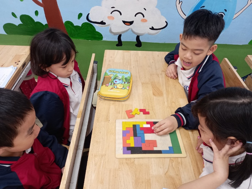 A group of children sitting at a table playing a puzzleDescription automatically generated